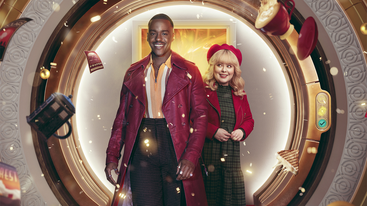 Ncuti Gatwa as the Doctor and Nicola Coughlan as Joy wearing red and green outfits with floating objects and glitter