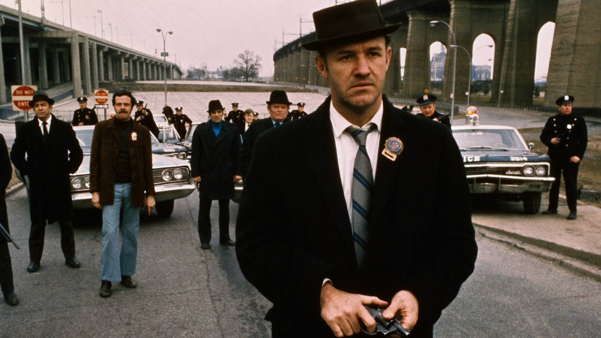 Policeman Gene Hackman is shown in this movie still walking toward the camera. He is holding a gun in his hands with policemen and police vehicles in the background. It was in this movie The French Connection that Gene Hackman won "Best Actor." The movie itself won "Best Picture."