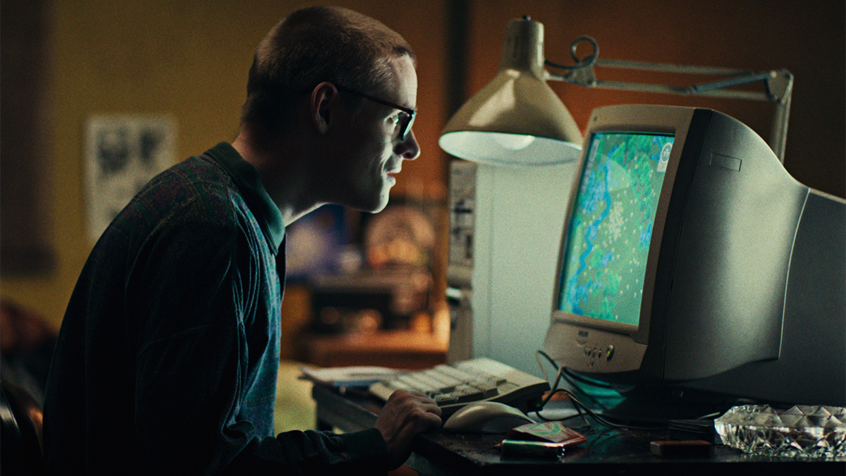 A short haired man looking at an old-fashioned computer monitor in Black Mirror season 7 episode "Plaything"