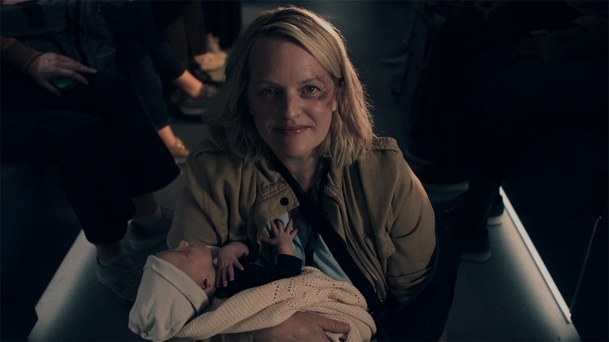 Elisabeth Moss smiling and holding a baby in The Handmaid's Tale season 6 episode 1